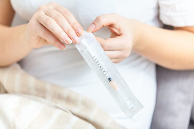 Woman opening single use syringe